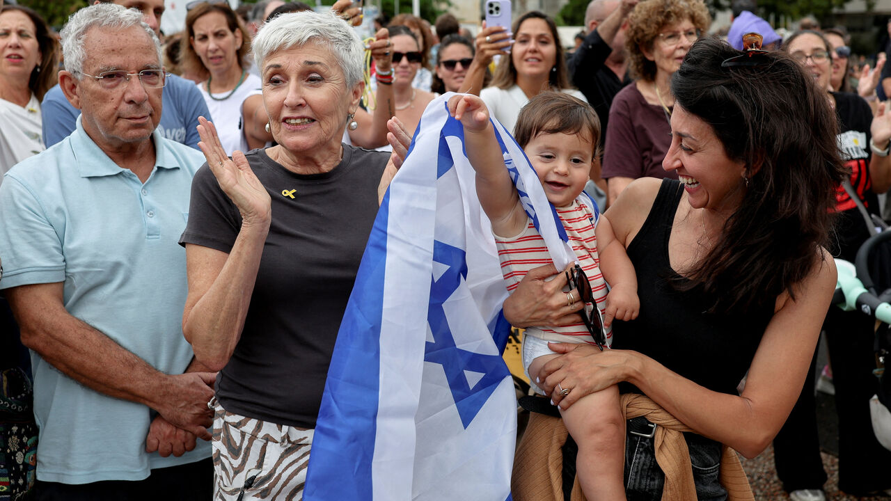 A child, with an Israeli flag draped around its shoulder, reacts as people gather to celebrate at the "Hostages square" after U.S. President Donald Trump announced that Israel and Hamas agreed on the first phase of a Gaza ceasefire, in Tel Aviv, Israel, October 9, 2025. REUTERS/Ronen Zvulun