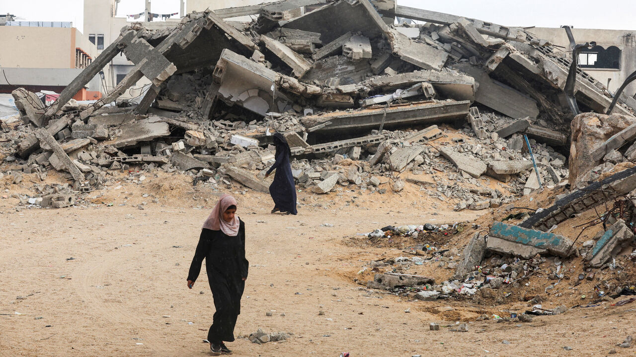 Palestinian women walk near rubble after a ceasefire, in Khan Younis in the southern Gaza Strip, October 9. REUTERS/Ramadan Abed