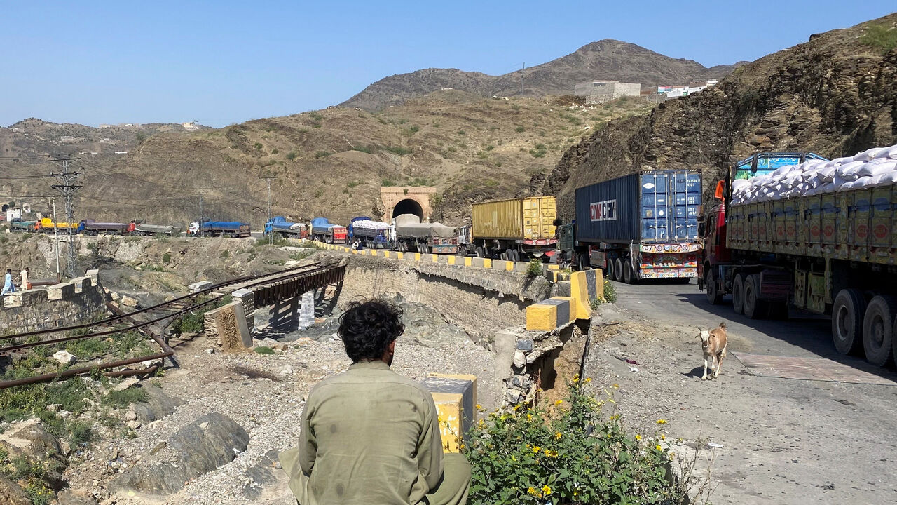 A man sits next to trucks parked at the Torkham border crossing, after Pakistan closed border crossings with Afghanistan, following exchanges of fire between the forces of the two countries, in Torkham, Pakistan, October 12, 2025. REUTERS/Shahid Shinwari