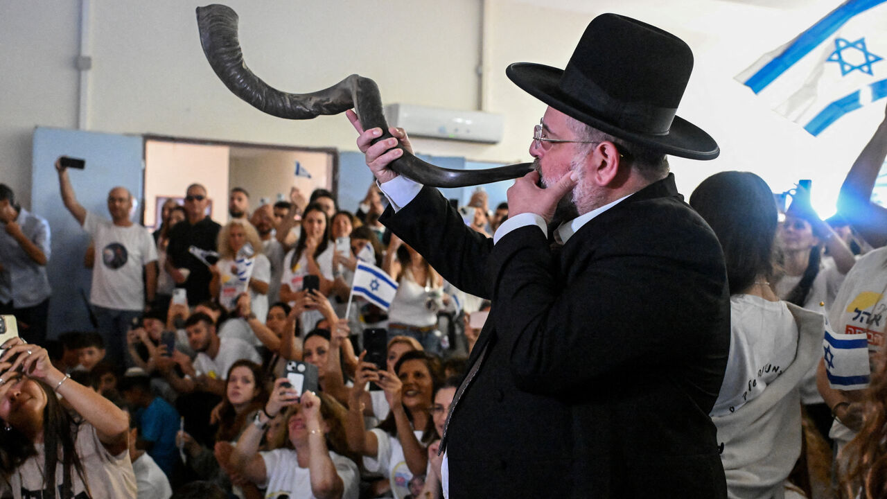 A man blows a shofar as relatives and friends of Israeli hostage Alon Ohel, held in Gaza since the deadly October 7, 2023 attack by Hamas, react as they watch broadcasts related to his release as part of a hostages-prisoners swap and a ceasefire deal in Gaza between Hamas and Israel, in Lavon, Israel October 13, 2025. REUTERS/Rami Shlush
