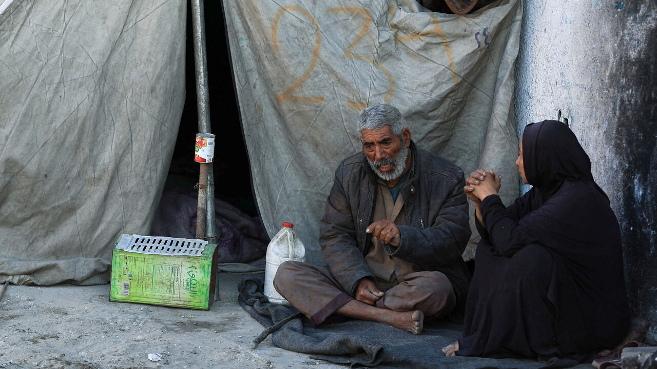 Palestinians sit next to a tent, amid a ceasefire between Israel and Hamas, in Gaza City, October 14, 2025. REUTERS/Dawoud Abu Alkas