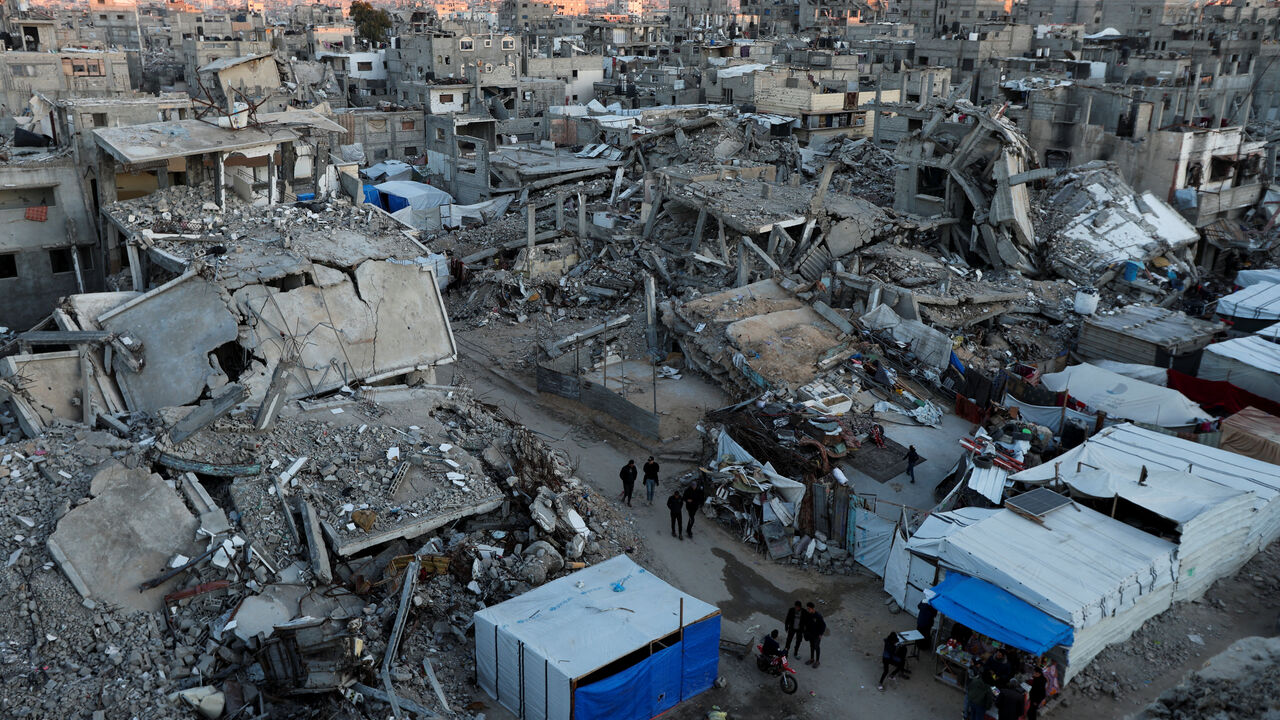 Palestinians walk past the rubble of buildings, amid a ceasefire between Israel and Hamas, in Khan Younis, in the southern Gaza Strip, February 27, 2025. REUTERS/Ramadan Abed