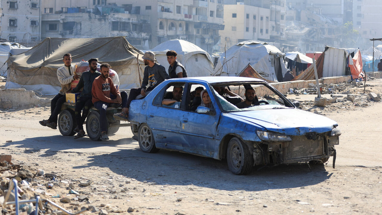 Palestinians in a car pull a cart with people on it, while driving near tents, amid a ceasefire between Israel and Hamas, in Gaza City, October 15, 2025. REUTERS/Dawoud Abu Alkas