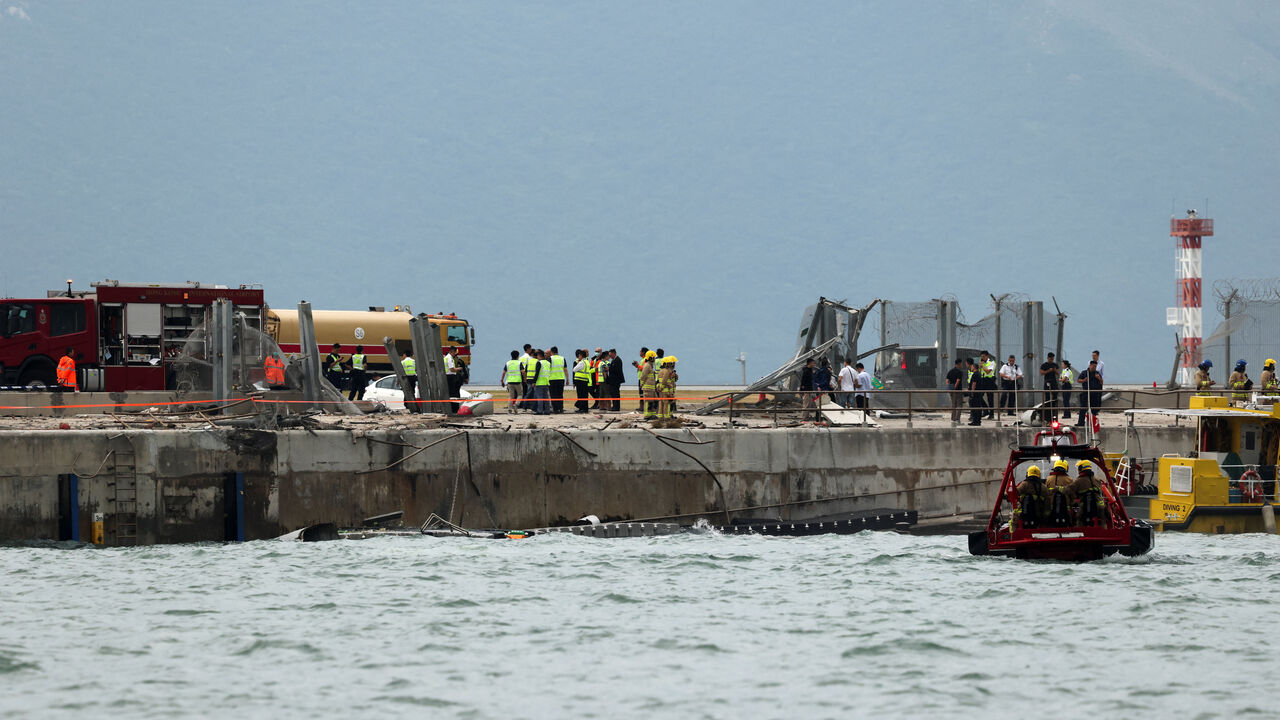 Emergency personnel gather near damaged fencing after a cargo plane veered off the runway during landing at Hong Kong International Airport in Hong Kong, China, October 20, 2025. REUTERS/Tyrone Siu
