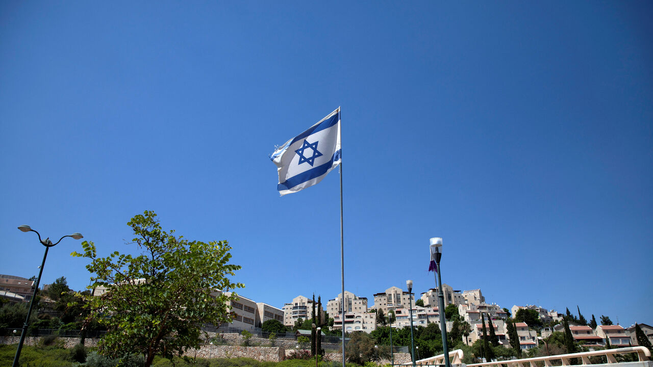 FILE PHOTO: The Israeli national flag flutters as apartments are seen in the background in the Israeli settlement of Maale Adumim in the Israeli-occupied West Bank August 16, 2020. Picture taken August 16, 2020. REUTERS/Ronen Zvulun/File Photo