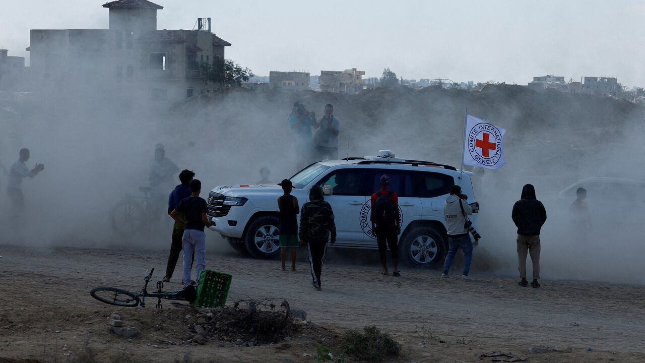 Palestinians gather around a Red Cross vehicle transporting hostages as part of a ceasefire and hostages-prisoners swap deal between Hamas and Israel, in the southern Gaza Strip, October 13. REUTERS/Mahmoud Issa