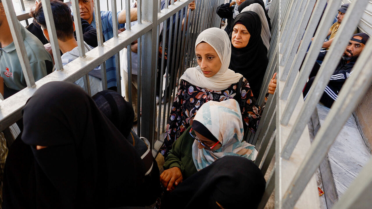 Palestinian women queue outside the Bank of Palestine amid a cash shortage, in Nuseirat, in the central Gaza Strip, October 27, 2025. REUTERS/Mahmoud Issa
