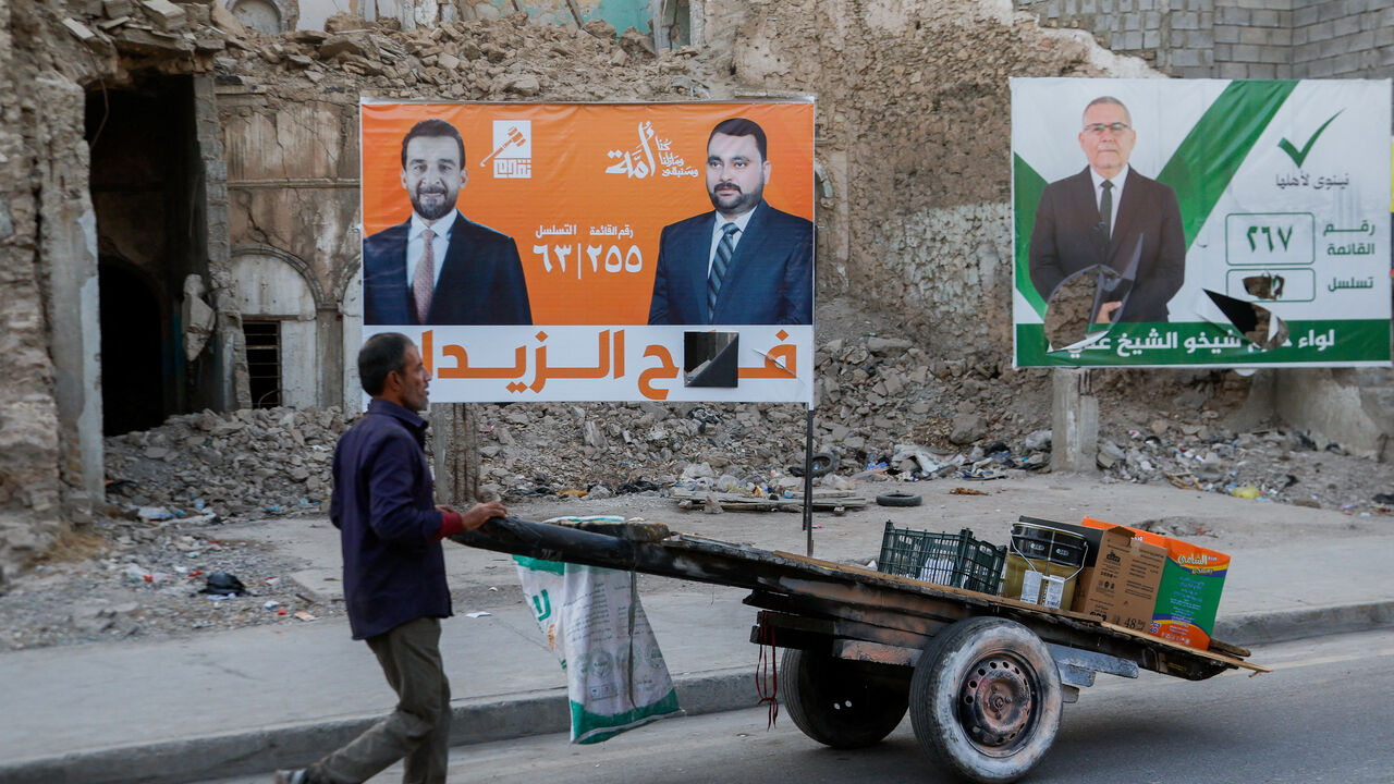 A man walks past campaign posters of Iraqi parliamentary candidates displayed on a street, ahead of the upcoming parliamentary elections, in Mosul, Iraq, October 29, 2025. REUTERS/Khalid al-Mousily