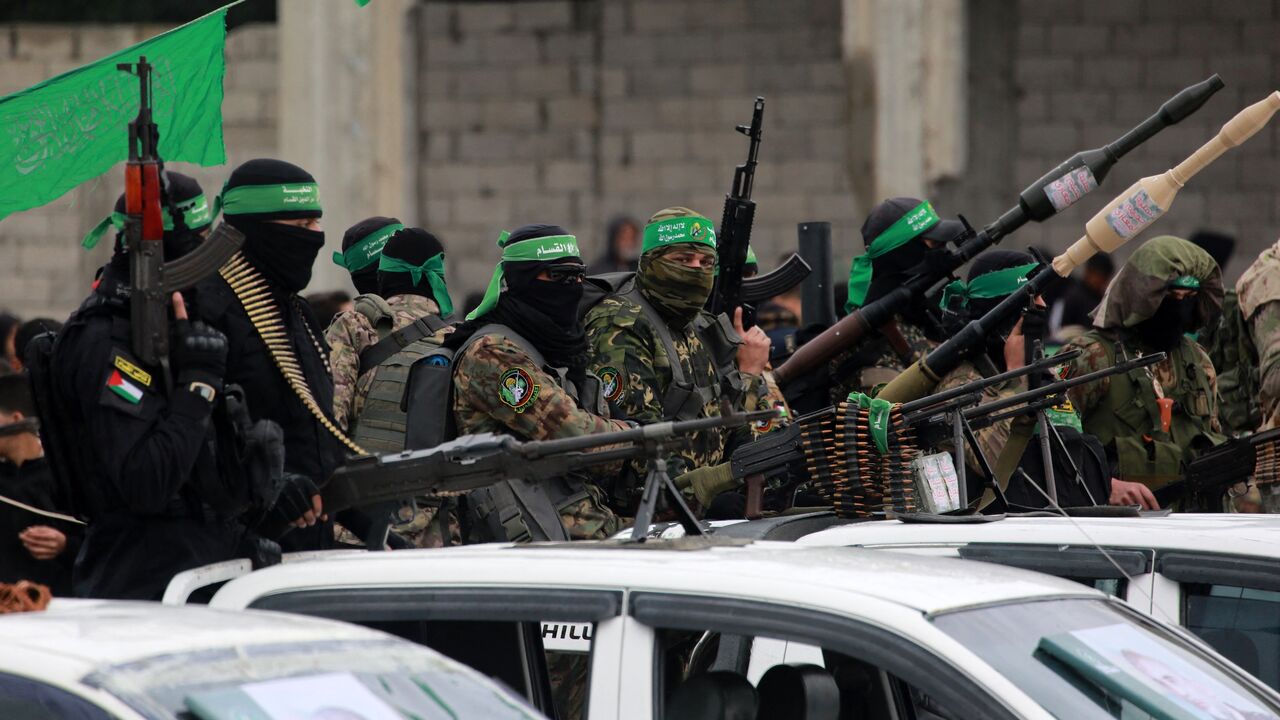 Palestinian Hamas fighters carry their guns in Nuseirat in the central Gaza Strip as preparations take place for the release of three Israeli hostages, as part of the seventh hostage-prisoner swap on Feb. 22, 2025.