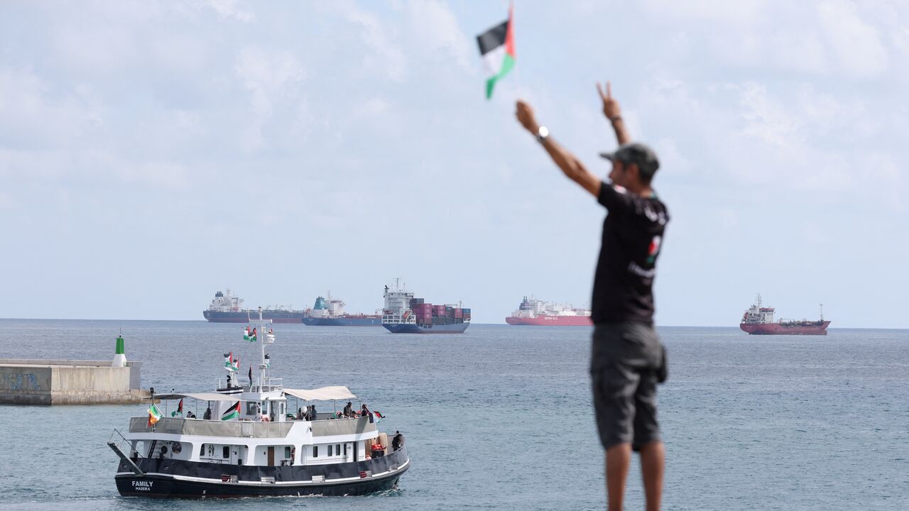 An activist waves the Palestinian flag as a boat carrying Swedish climate activist Greta Thunberg and activists.