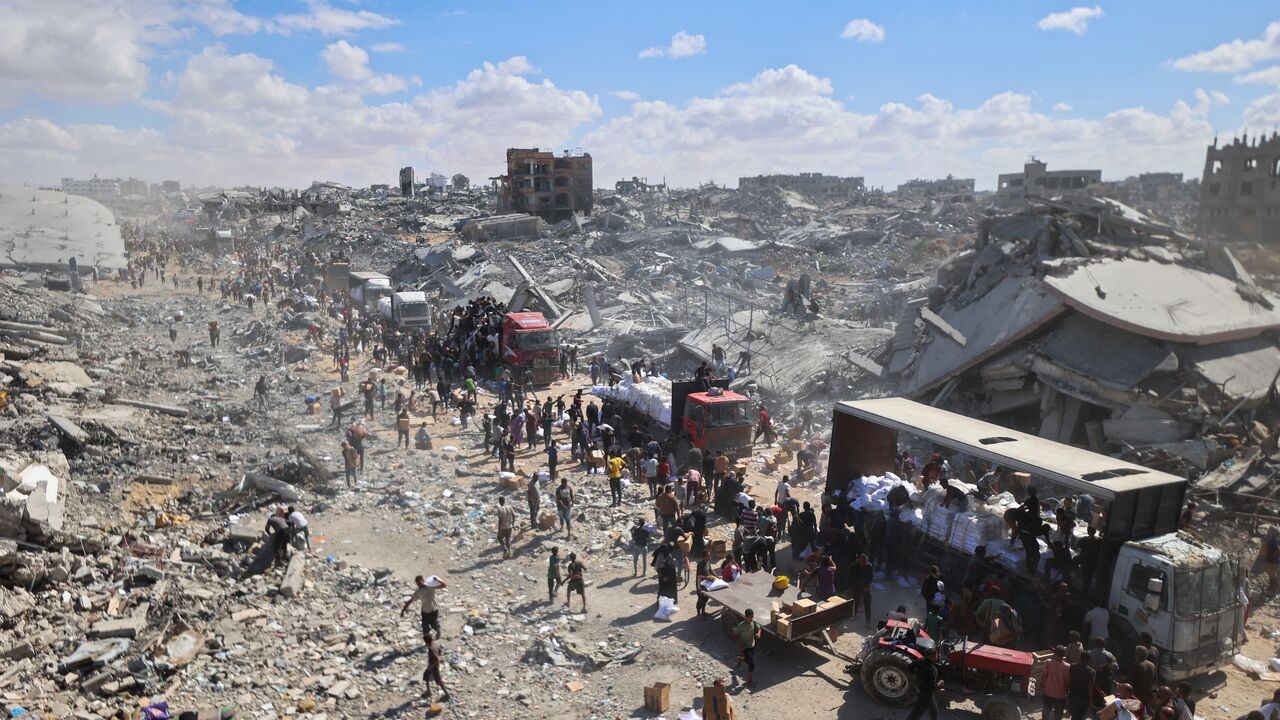Palestinians rally around aid trucks which entered from the Karem Abu Salem crossing, in Khan Yunis in the southern Gaza Strip on Oct. 12, 2025.