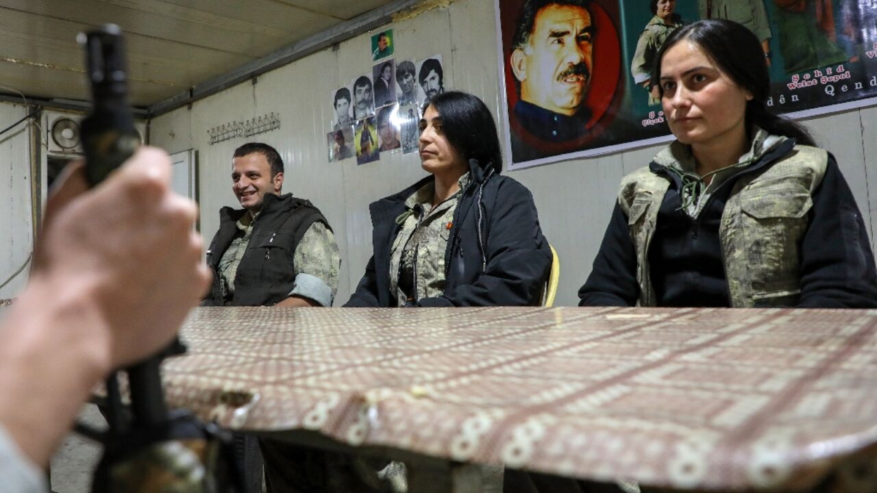 PKK members sit under a portrait of their jailed leader Abdullah Ocalan in a cave network in the Qandil mountains