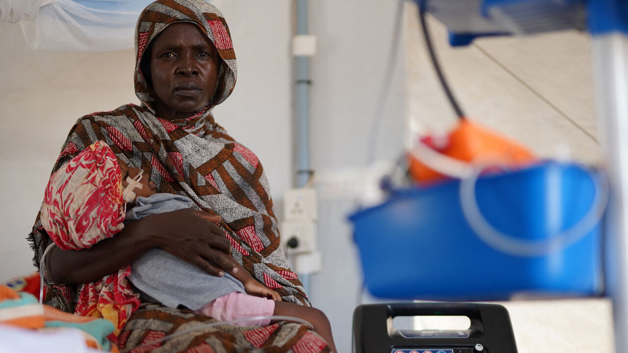 An injured displaced Sudanese woman who fled violence in al-Fashir receives treatment while carrying her child at a makeshift clinic run by Medecins Sans Frontieres (MSF), amid ongoing clashes between the paramilitary Rapid Support Forces (RSF) and the Sudanese army, in Tawila, North Darfur, Sudan November 3, 2025. REUTERS/Mohamed Jamal