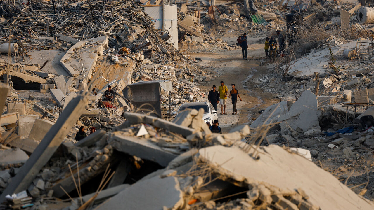 Palestinians walk past the rubble of destroyed buildings, amid a ceasefire between Israel and Hamas, in Jabalia, northern Gaza Strip, November 6, 2025. REUTERS/Mahmoud Issa