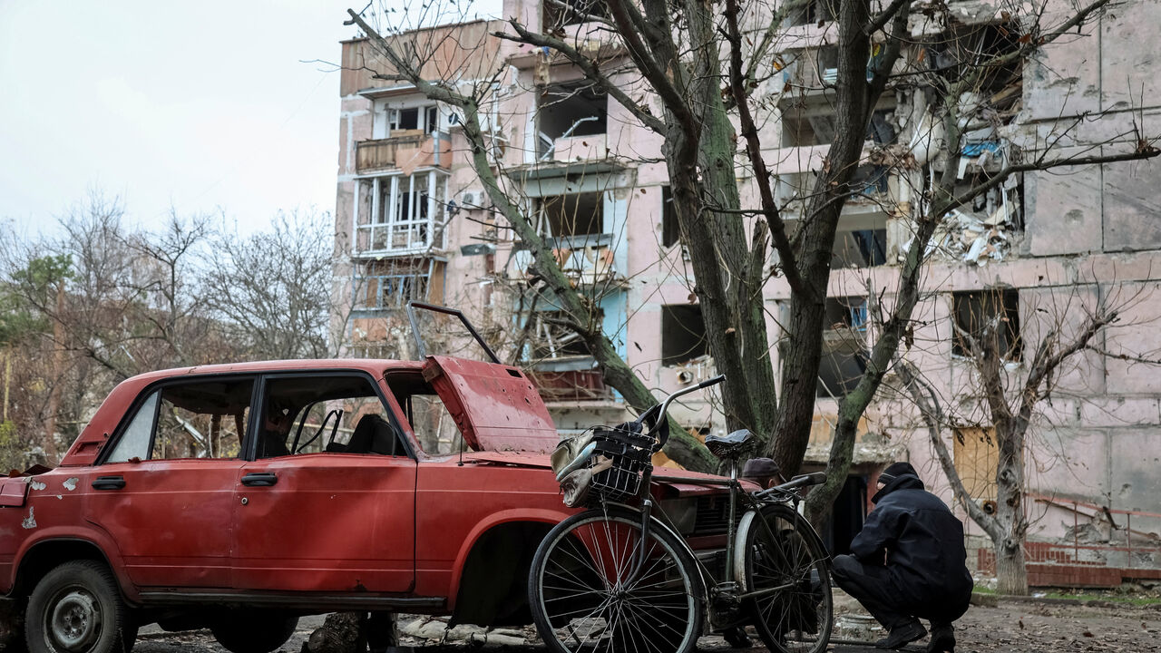 A resident hides from a Russian FPV drone behind a damaged car, amid Russia's attack on Ukraine, in the frontline town of Huliaipole in Zaporizhzhia region, Ukraine November 11, 2025. REUTERS/Sergiy Chalyi      TPX IMAGES OF THE DAY