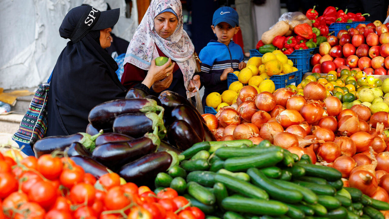 Palestinians buy vegetables at a market in Nuseirat, central Gaza Strip, November 13, 2025. REUTERS/Mahmoud Issa