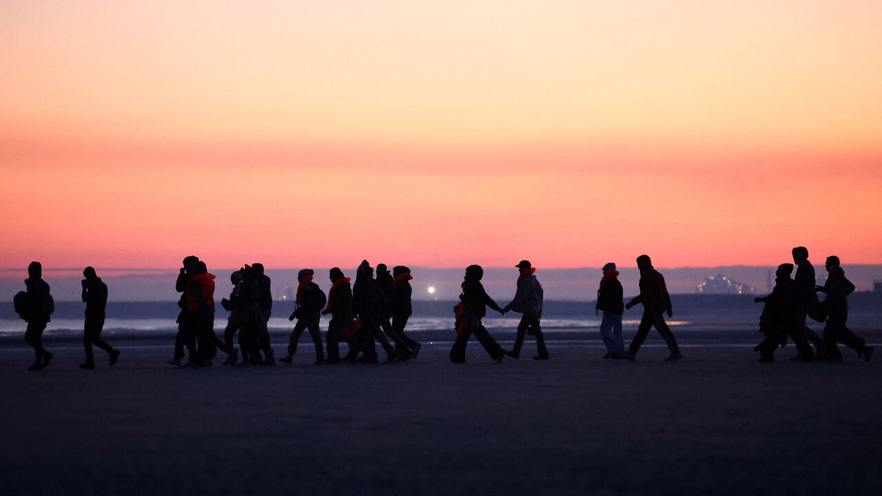 Migrants walk along the beach before trying to board an inflatable dinghy leaving the coast of northern France in an attempt to cross the English Channel to reach Britain, from the beach of Petit-Fort-Philippe in Gravelines, near Calais, France, September 27, 2025. REUTERS/Abdul Saboor