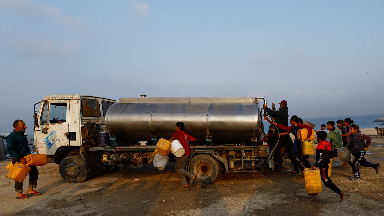 Displaced Palestinians run to fill containers with water amid a ceasefire between Israel and Hamas, in Gaza City, November 6, 2025. REUTERS/Mahmoud Issa