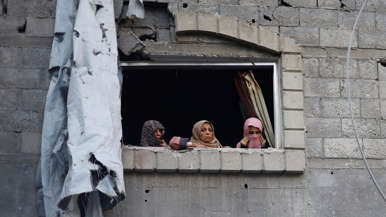 Palestinian women look out of a window near the site of Saturday's Israeli strike in the Central Gaza Strip, November 23, 2025. REUTERS/Mahmoud Issa/File Photo