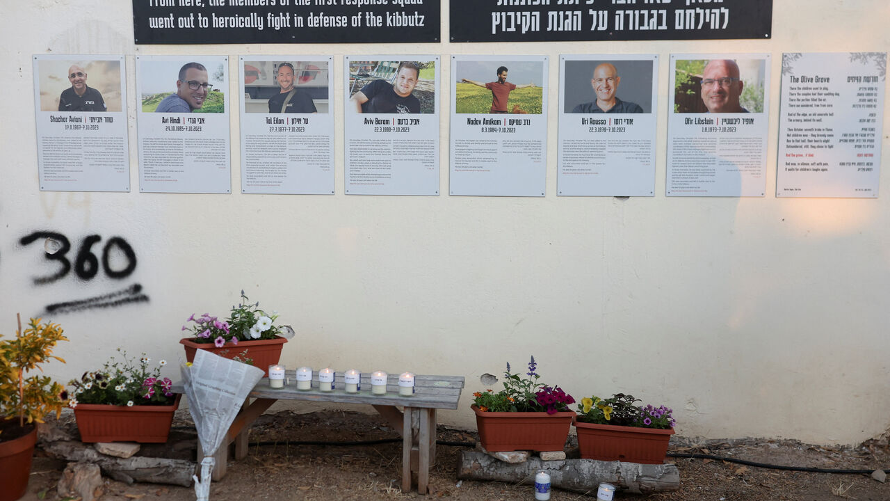 Flower tributes and candles are places in front of posters on a wall during a memorial to commemorate the two-year anniversary of the deadly October 7, 2023 attack on Israel by Hamas from Gaza, in Kibbutz Kfar Aza, southern Israel, October 7, 2025. REUTERS/Ronen Zvulun