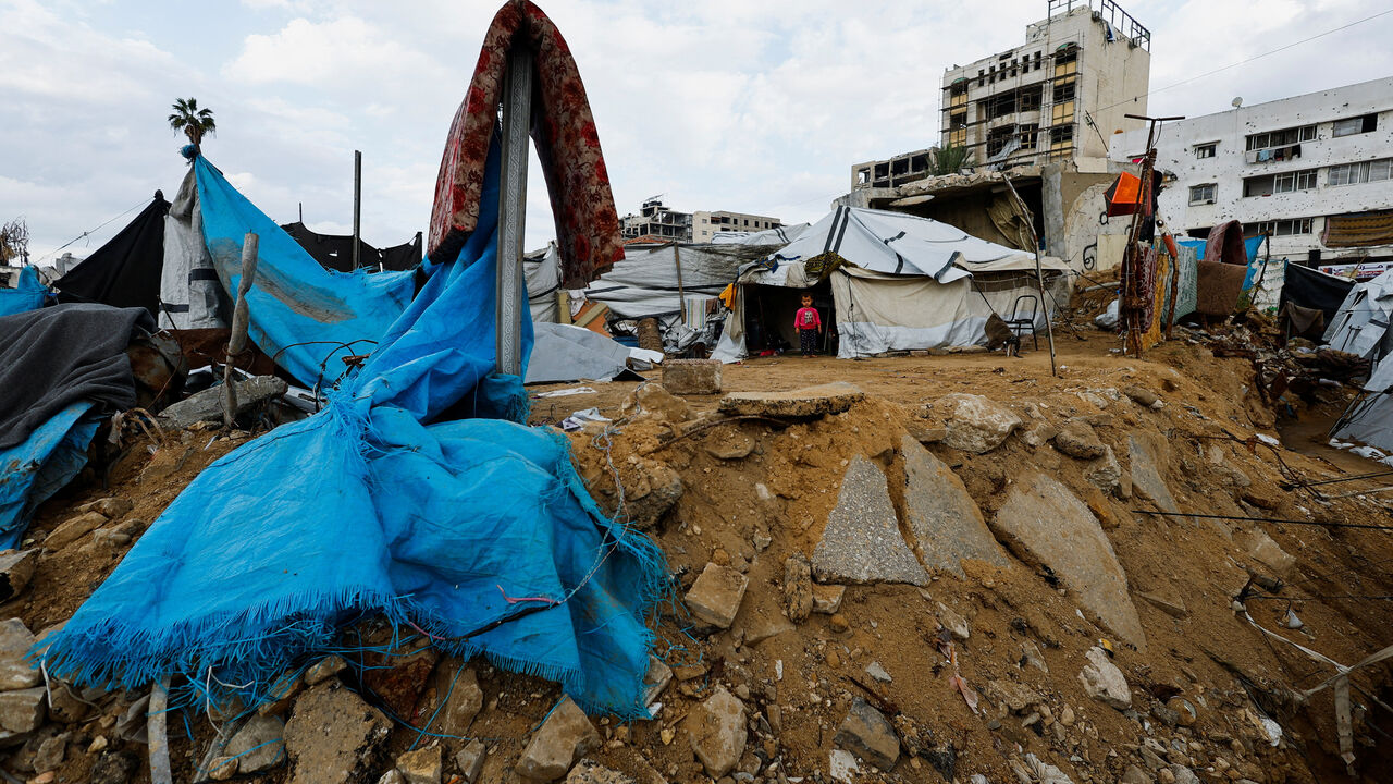 A Palestinian child stands in front of a tent on a rainy day in Gaza City, November 25, 2025. REUTERS/Mahmoud Issa