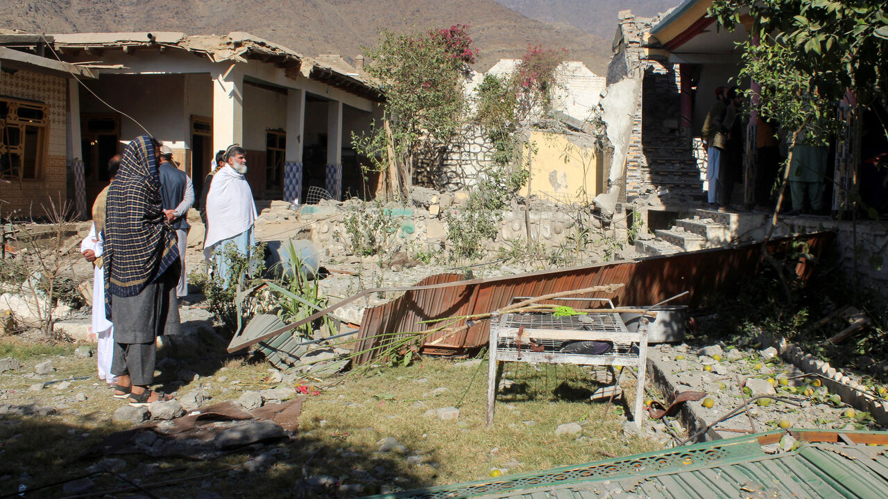 People stand in front of damaged houses that the Afghan Taliban government said were damaged after Pakistan carried out raids, in Asadabad, Kunar province, Afghanistan, November 25, 2025. REUTERS/Stringer
