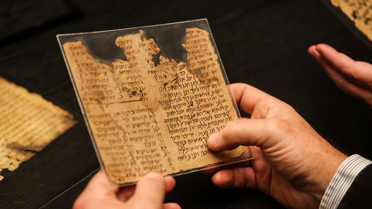 A researcher of MiDRASH, a project dedicated to analysing the National Library of Israel’s digital database of all known Hebrew manuscripts using Machine Learning, including manuscripts from the Cairo Geniza, holds fragments of an aggadic-midrashic work of Torah exegesis and retellings of biblical stories, in Jerusalem November 24, 2025. REUTERS/Ronen Zvulun
