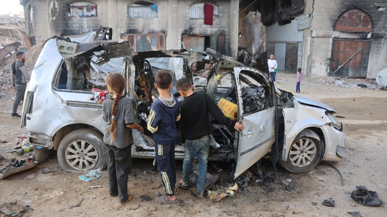 Palestinian children look at a destroyed vehicle in Gaza City