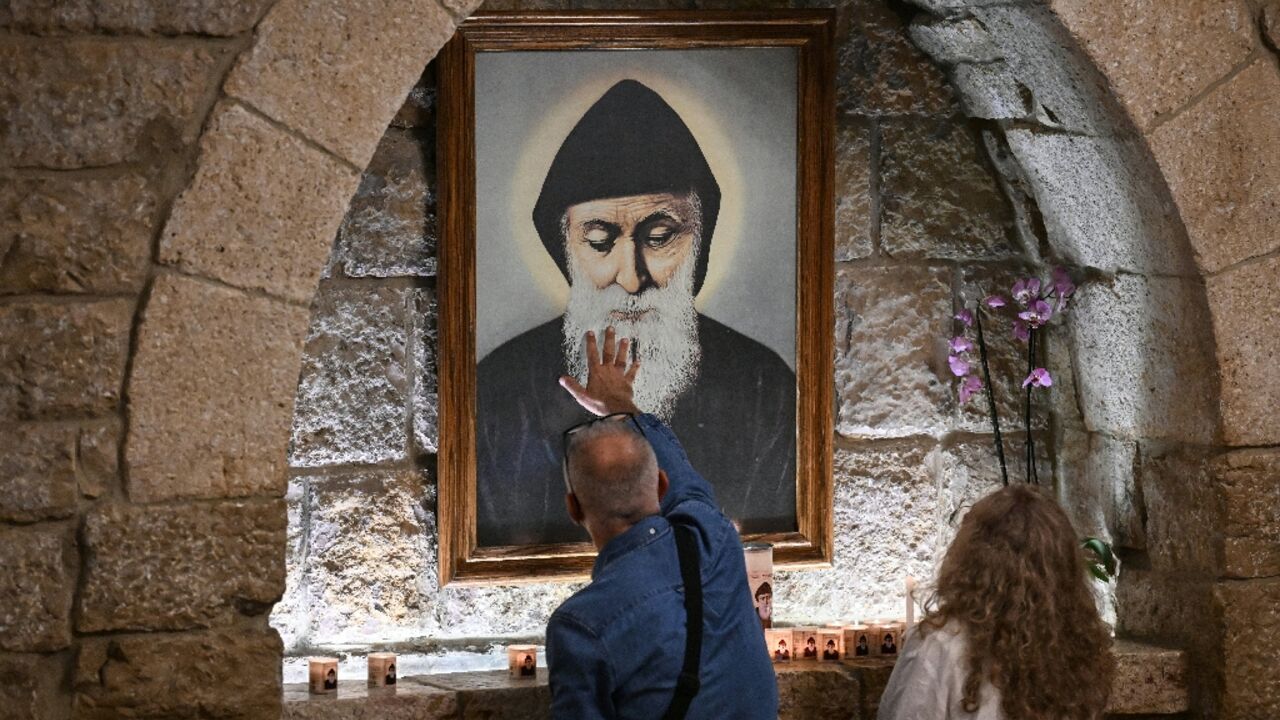 Pilgrims in front of a portrait of Saint Charbel at the monastery of Saint Maron in Lebanon's mountain village of Annaya