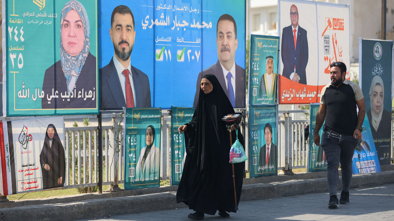 Iraqis walk past electoral billboards, including one bearing a portrait of Prime Minister Mohammed Shia al-Sudani (C), in central Baghdad on Oct. 19, 2025, ahead of Iraq's parliamentary elections on Nov. 11. 