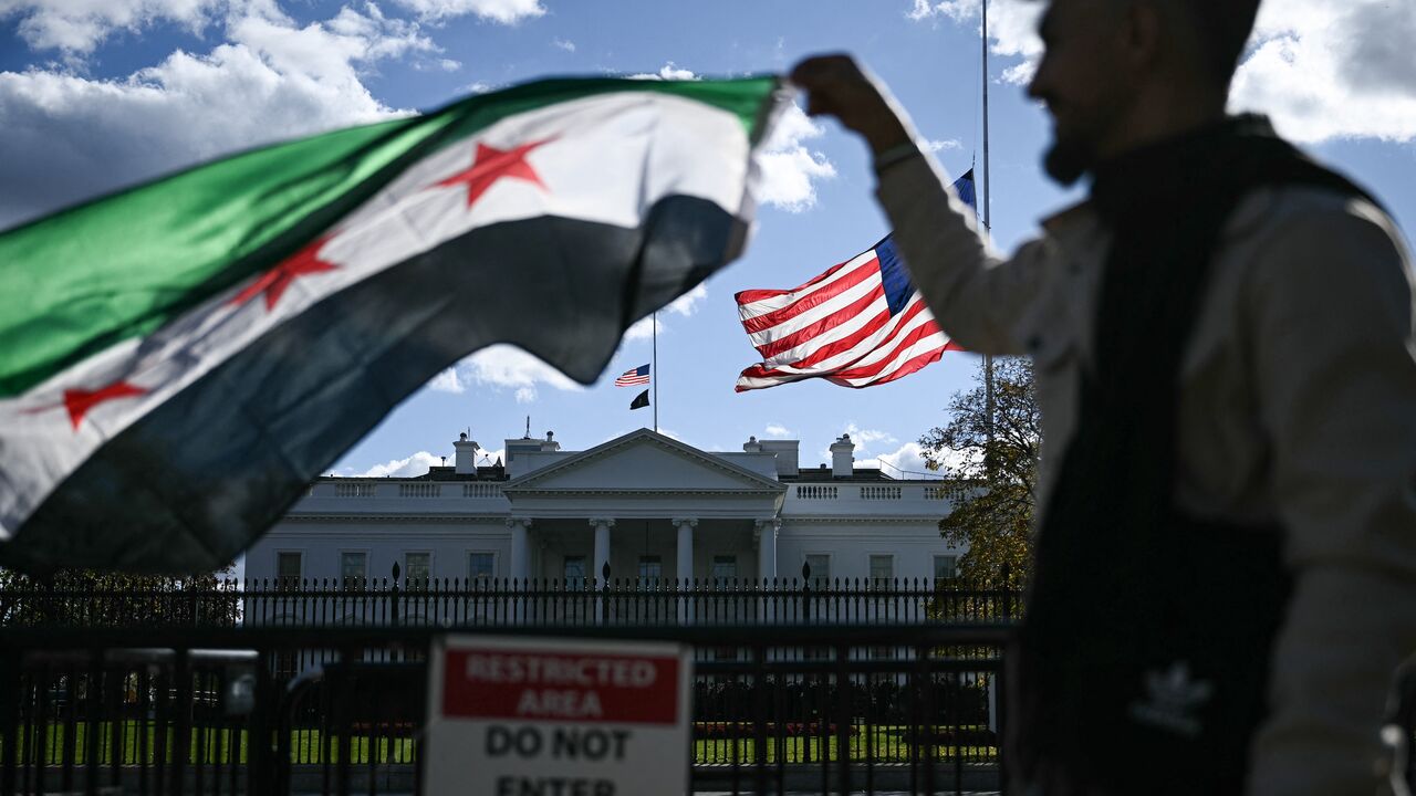 A man holds a Syrian flag across the street from the White House after Syrian President Ahmed al-Sharaa met with US President Donald Trump at White House in Washington on Nov. 10, 2025. 