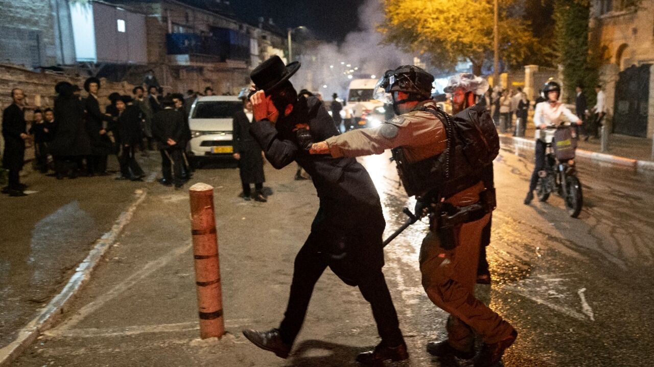 An Israeli police officer disperses an ultra-Orthodox Jewish demonstrator during a protest against conscription