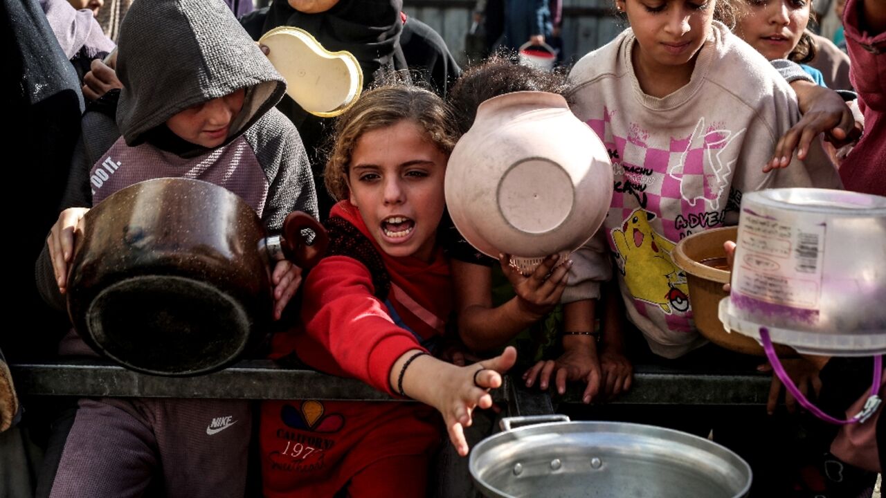 Displaced Palestinian children waited for food at a shelter in Nuseirat, Gaza, in November 2025