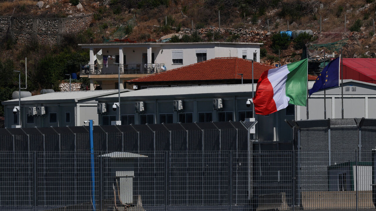 FILE PHOTO: An Italian and a European Union flag flutter at a reception camp set up as part of an Italian government plan to process migrants rescued at sea, in Shengjin, Albania, July 31, 2025. REUTERS/Florion Goga/File Photo