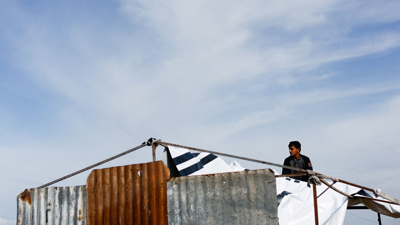 FILE PHOTO: A displaced Palestinian shelters at a tent camp in Deir Al-Balah, in the central Gaza Strip, December 9, 2025. REUTERS/Mahmoud Issa/ File Photo