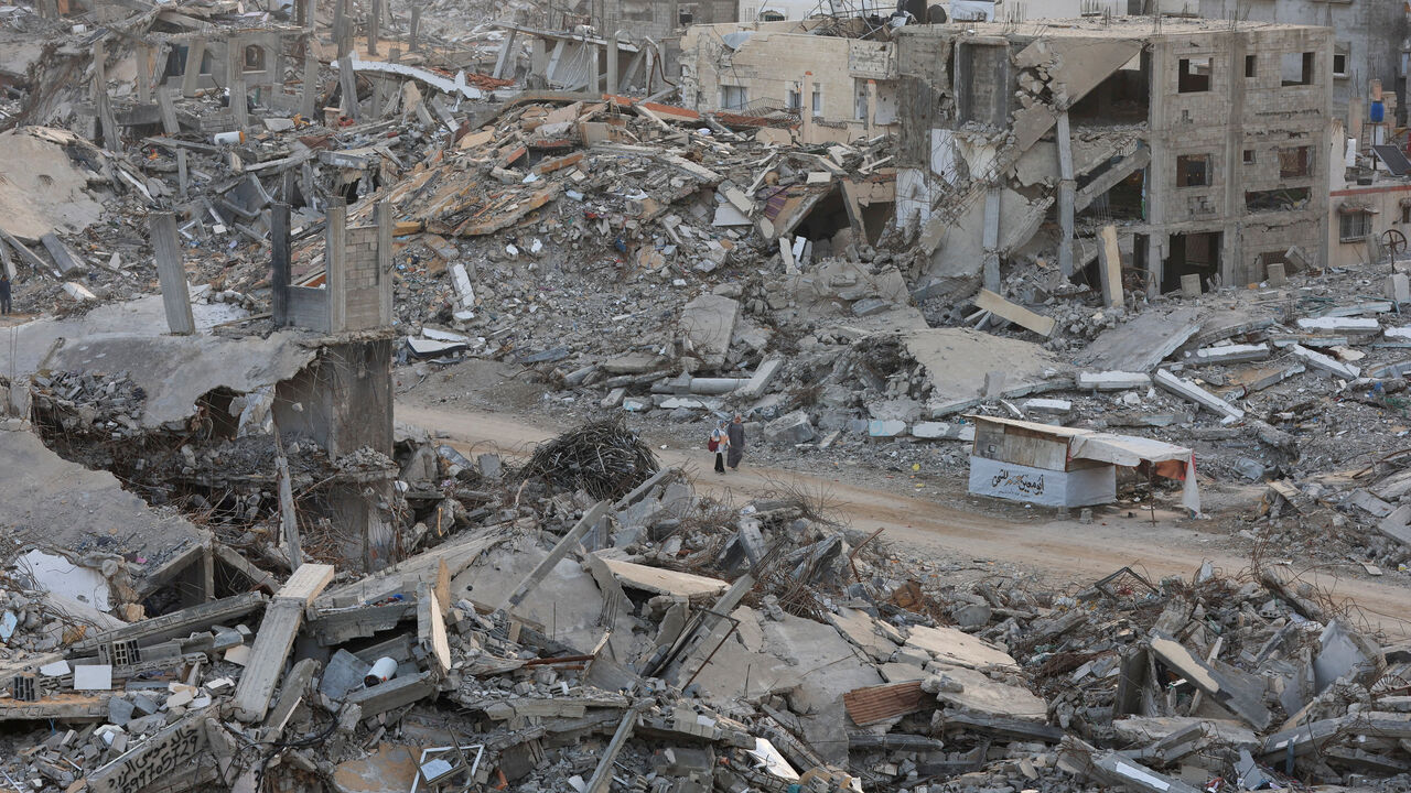 FILE PHOTO: Palestinian women walk among piles of rubble and damaged buildings, in Gaza City, November 24, 2025. REUTERS/Dawoud Abu Alkas/File Photo
