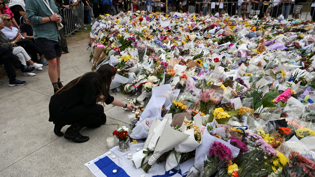 A woman keeps a candle next to flowers laid as a tribute at Bondi Beach to honour the victims of a mass shooting that targeted a Hanukkah celebration at Bondi Beach on Sunday, in Sydney, Australia, December 16, 2025. REUTERS/Flavio Brancaleone