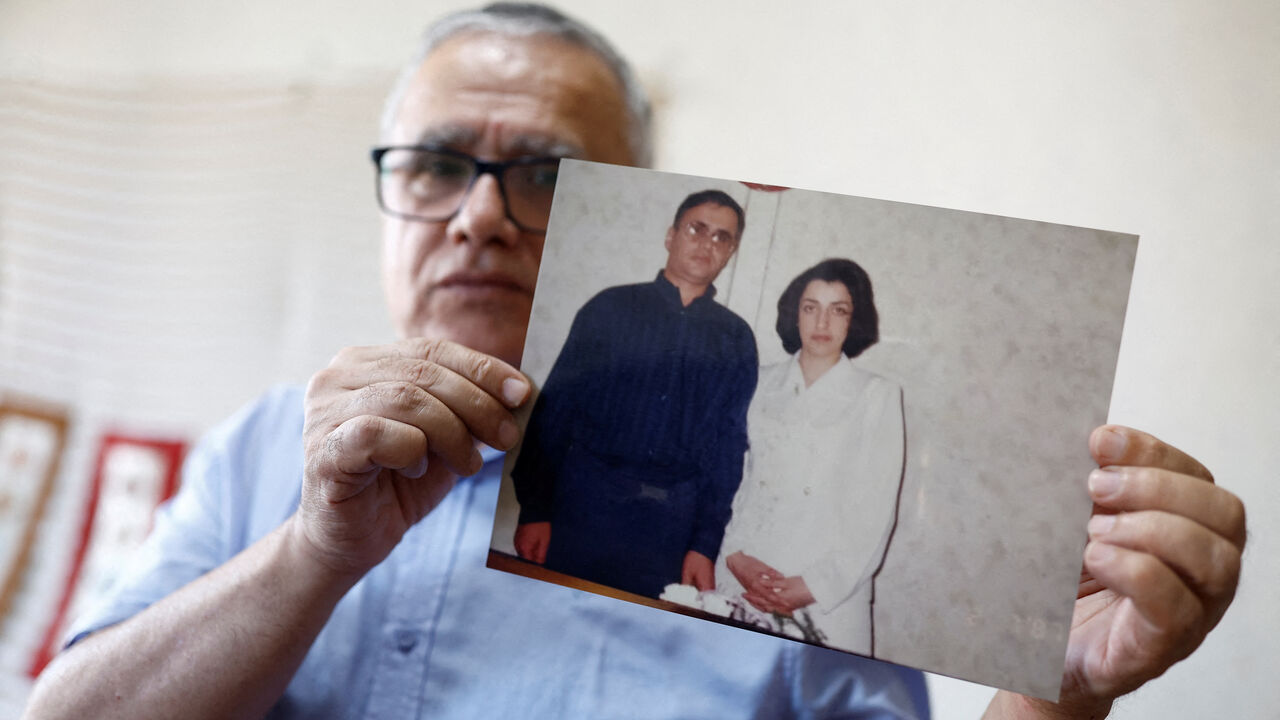 FILE PHOTO: Taghi Ramahi, husband of Narges Mohammadi, a jailed Iranian women's rights advocate, who won the 2023 Nobel Peace Prize, poses with an undated photo of himself and his wife, during an interview at his home in Paris, France, October 6, 2023. REUTERS/Christian Hartmann/File Photo