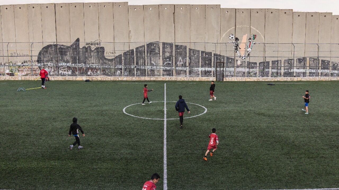 Palestinian youths train at the Aida Refugee Camp's football pitch, next to the separation wall outside Bethlehem, under threat of demolition by Israeli authorities