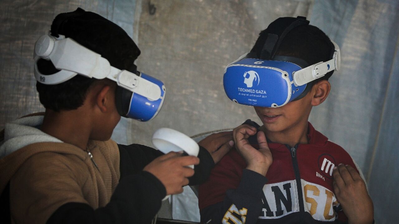 Palestinian children using goggles and a joystick experience virtual reality as part of a therapy programme