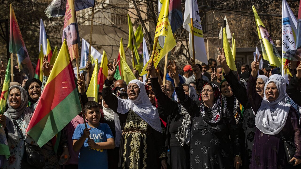 Syrian Kurds lift placards and flags during a rally calling for an autonomous administration and Kurdish rights in Syria's predominantly Kurdish northeastern city of Qamishli, on Sept. 17, 2025.