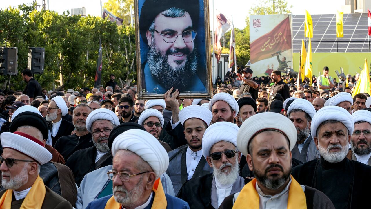 A Shiite Muslim cleric holds a picture of Hassan Nasrallah.