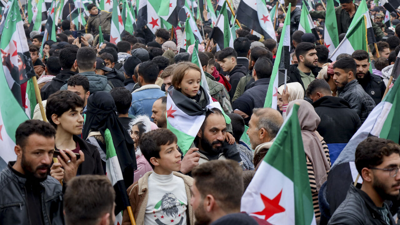 Thousands of people wave Syrian flags as they gather in a square during an anniversary rally in Idlib, Syria, on Dec. 8, 2025. (Photo by Omar Albaw/Middle East Images/AFP via Getty Images)