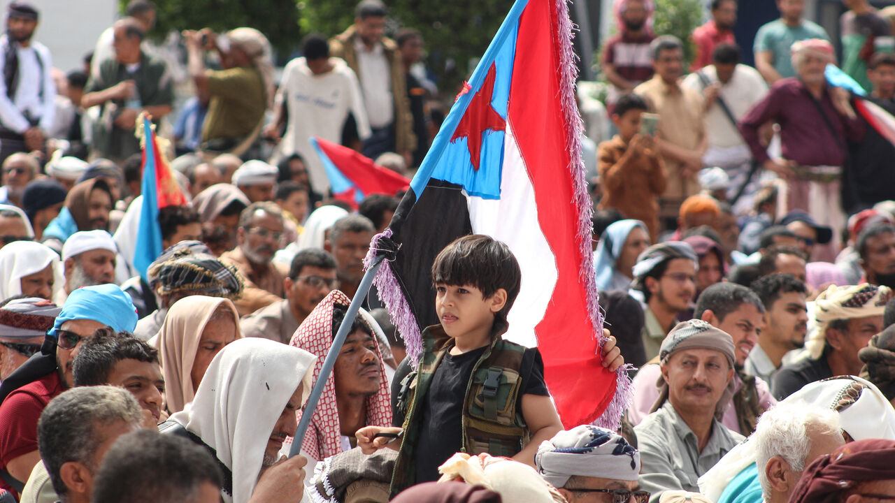 A boy looks on as supporters of the Southern Transitional Council (STC), a coalition of separatist groups seeking to restore the state of South Yemen, hold South Yemen flags during a rally calling for the revival of the former independent state, in Aden on December 12, 2025. The UAE-backed Southern Transitional Council last week swept through swathes of Yemen in a near-bloodless takeover they say aimed to expel Islamists and halt smuggling for the benefit of the Iran-backed Houthis. (Photo by Saleh Al-OBEID