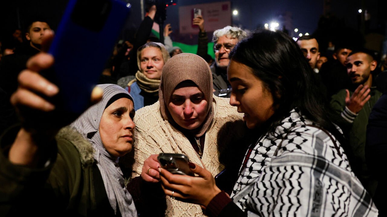 Women look at a mobile phone screen in Ramallah, in the Israeli-occupied West Bank, January 20, 2025. REUTERS/Ammar Awad/File Photo