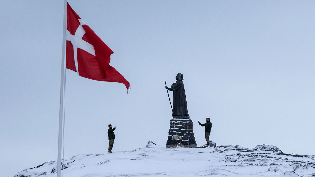 Danish soldiers take pictures next to the statue of Hans Egede, at Nuuk's old harbour, Greenland, January 18, 2026. REUTERS/Marko Djurica