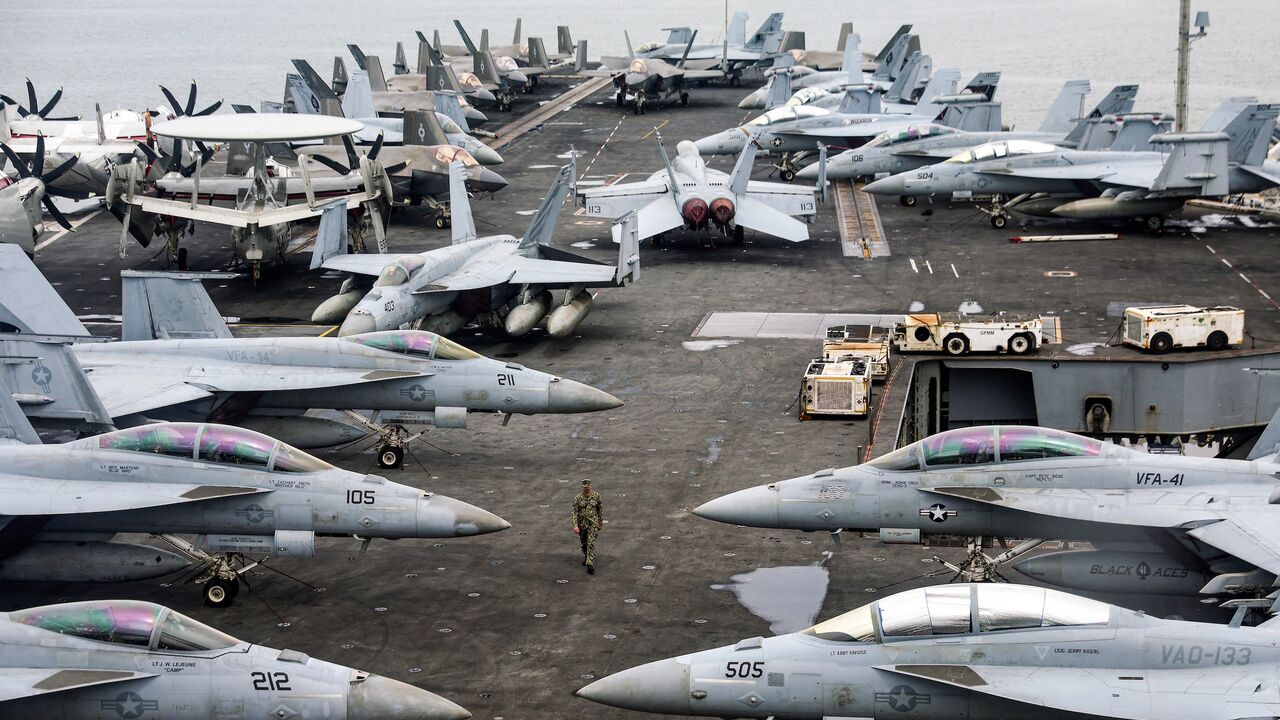 A US Navy officer walks past fighter jets parked on the flight deck of the Nimitz-class aircraft carrier USS Abraham, Kuala Lumpur, Nov. 26, 2024