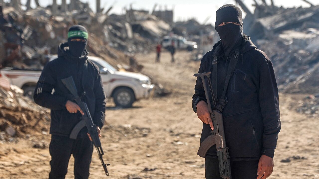 Palestinian Hamas militants secure the area as Egyptian workers, accompanied by members of the International Committee of the Red Cross, search for the last two remaining bodies of hostages from under the rubble of the Jabalia refugee camp, in the northern of Gaza Strip on Dec. 1, 2025. 