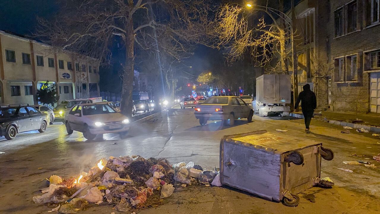 Burning debris lies next to an overturned dumpster in the middle of a street during unrest amid demonstrations in Hamedan, Iran, on January 1, 2026. The demonstrations erupted after shopkeepers in Tehran's Grand Bazaar shut their businesses to protest the sharp fall of Iran's currency and worsening economic conditions, with clashes reported in several provinces and Iranian media and rights groups saying multiple people were killed in the violence, marking the largest protests to hit the Islamic Republic in 