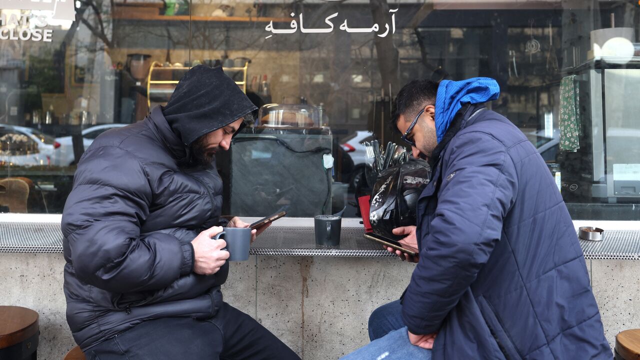 Men use their mobile phones while sitting at a coffee shop in Tehran, on Jan. 7, 2026.